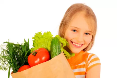 Una niña sostiene una bolsa con verduras