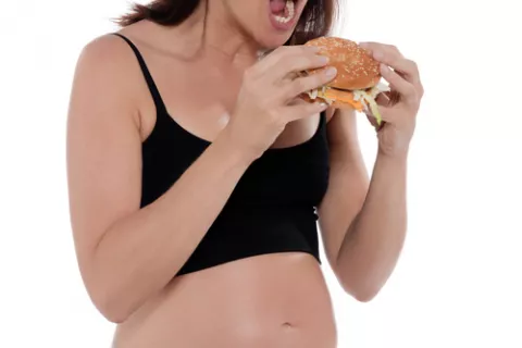 Mujer embarazada comiendo una hamburguesa