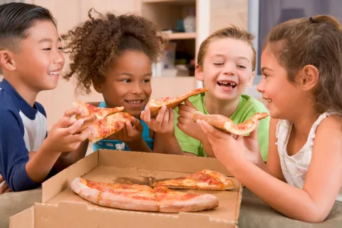 Grupo de niños comiendo pizza