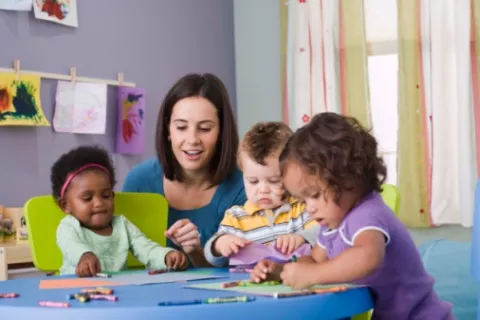 Niños juegan en la guardería supervisados por una profesional