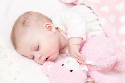 Bebé durmiendo junto a un peluche