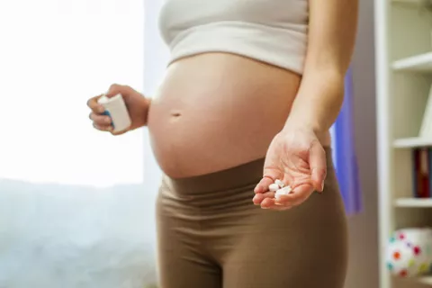 Mujer embarazada mostrando un puñado de pastillas