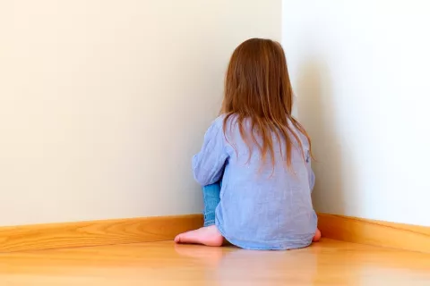 Niña sentada de cara a la pared