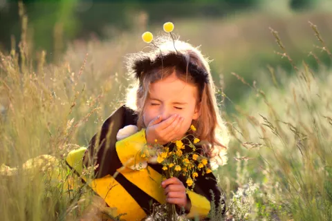 Niña pequeña estornudando en el campo