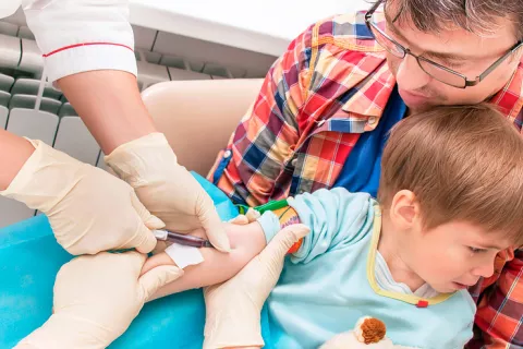 Doctor haciendo un análisis de sangre a un niño.