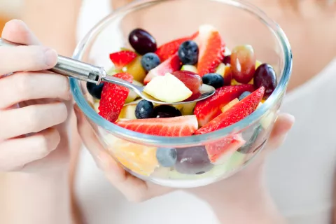 Una mujer se dispone a comer una ensalada de frutas