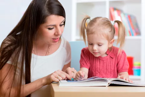 Madre enseñando a leer a su hija