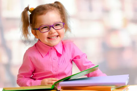 Niña pequeña con gafas sonriendo a la cámara