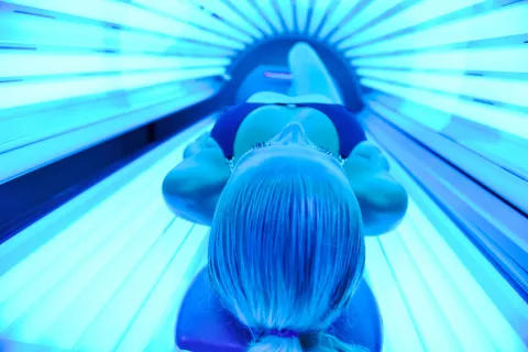 Chica joven en una cabina de bronceado