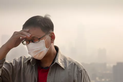 Hombre chino con mascarilla al aire libre con elevados niveles de contaminación atemosférica