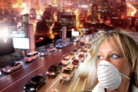 Mujer con mascarilla en una gran ciudad con contaminación