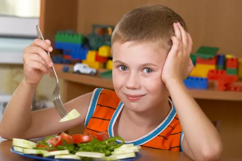 Niño con asma tomando un plato de dieta mediterránea