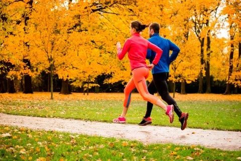 Pareja corriendo por el parque en fin de semana