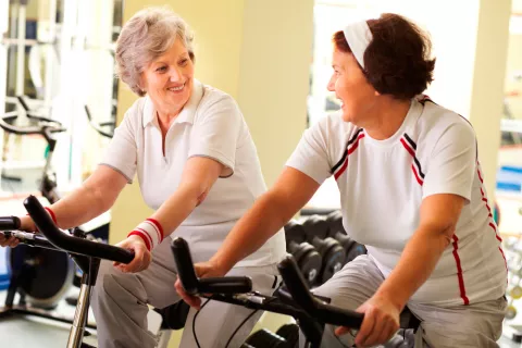 Dos mujeres mayores realizan ejercicio en bicicleta estática