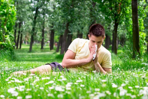 Un joven alérgico se suena la nariz en el campo