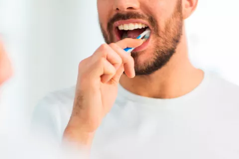 Un hombre se cepilla los dientes frente al espejo