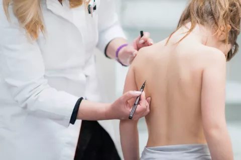 Una doctora examina la espalda de una niña