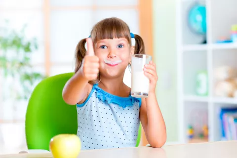 Niña bebiendo un vaso de leche entera