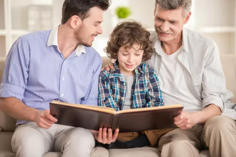 Abuelo, padre e hijo leen juntos un libro