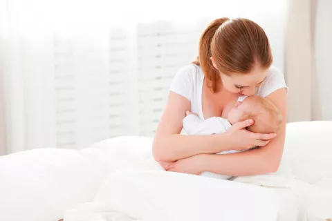 Madre acunando con el brazo izquierdo a su bebé