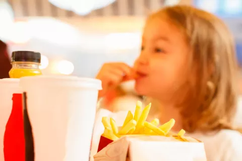 Niña comiendo comida rápida preprocesada