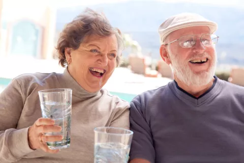 Una pareja mayor sostiene dos grandes vasos de agua