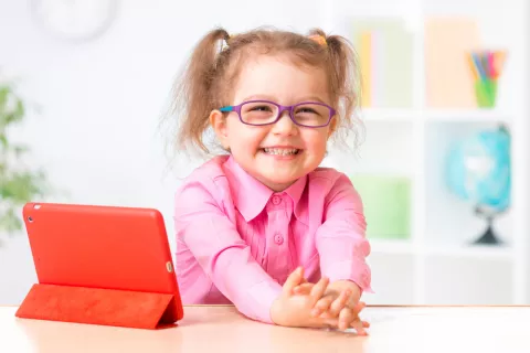 Niña pequeña con gafas sonríe a la cámara