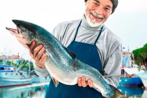 Un pescador sujeta un salmón en sus manos