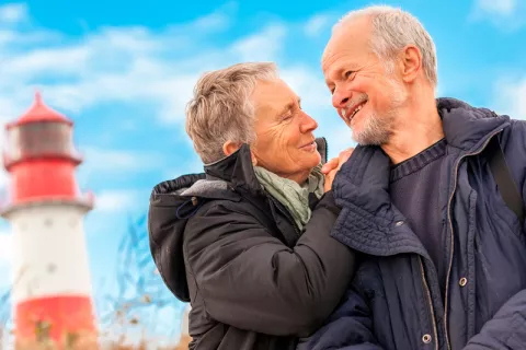 Pareja de ancianos pasean junto a un faro