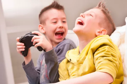 Dos niños ríen a carcajadas con un videojuego