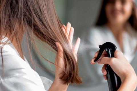 Mujer joven aplicando alisador químico a su pelo