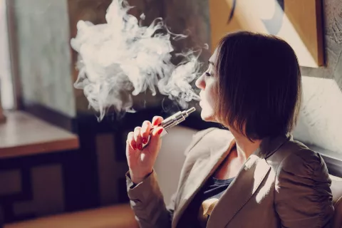 Chica joven fumando un cigarrillo electrónico