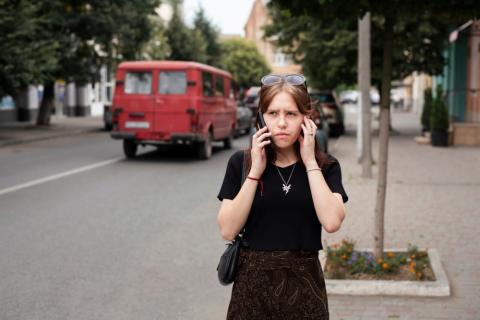 Mujer joven hablando por teléfono en medio del tráfico de una ciudad
