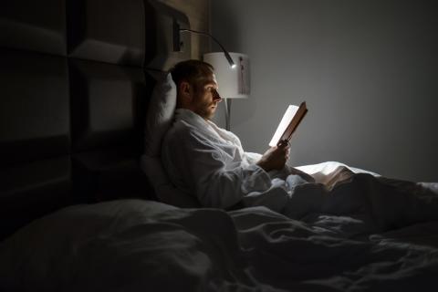 Persona joven leyendo por la noche en la cama