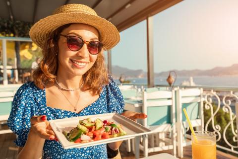 Mujer comiendo una ensalada de verano junto al mar