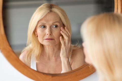 Una mujer mayor observando como cambia su rostro en el espejo
