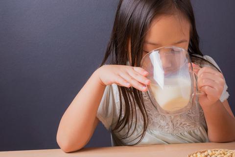 Niña bebiendo vaso de leche de soja