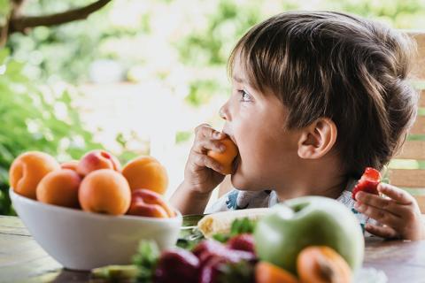 Niño comiendo fruta al aire libre