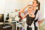 Usar mal los portabebés podría aumentar el riesgo de lesiones en bebés Madre haciendo tareas del hogar y llevando a su bebé en el portabebé