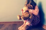 El maltrato infantil aumenta el riesgo de varios trastornos mentales Niña triste sentada en un rincón de una habitación