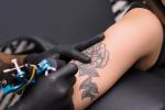 Un tatuador realizando un tatuaje a una chica en el brazo
