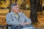 Anciano con la mirada perdida sentado en el parque
