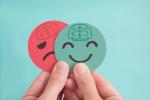 Una persona sujeta dos emojis, uno positivo y otro negativo