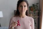 Mujer joven sostiene lazo rosa símbolo de cáncer de mama