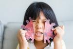 Niño rompiendo una silueta del virus COVID-19 hecha en papel