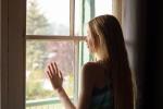 Chica adolescente mira por la ventana durante el confinamiento