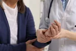Mujer con síntomas de artritis reumatoide en la mano Médico examina la mano de una mujer con síntomas de artritis