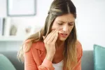 Mujer con problemas de salud bucodental como caries o periodontitis Mujer se toca un lado de la mandíbula con gesto de dolor