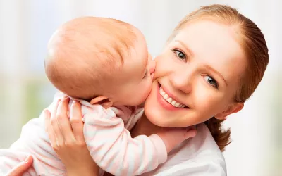 Instinto materno: ¿Mito o realidad? Un bebé besa a su madre mientras esta lo sostiene en brazos