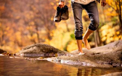 Hombre caminando descalzo por la orilla de un río